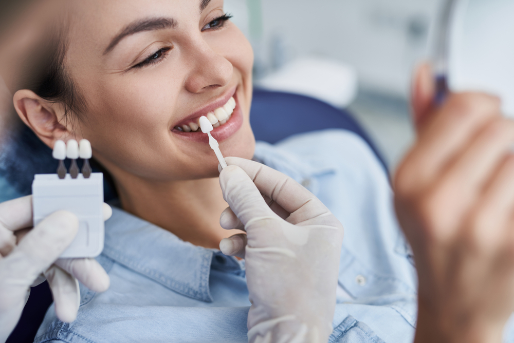Cosmetic Dental Consultation – Dentist Tacoma Smiling woman undergoing cosmetic dental consultation with shade guide – Dentist Tacoma