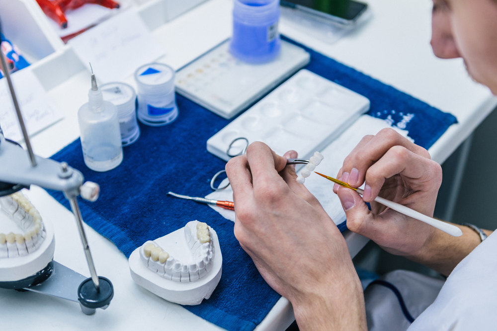 Dental Technician Crafting Custom Dentures in Lab – Dentures A close-up of a dental technician working with tools and materials to shape and detail custom dentures in a lab setting – Dentures