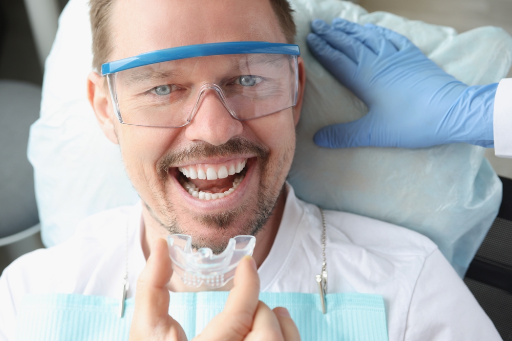 Smile Protection with Night Guard – Dentist Tacoma Male dental patient holding a night guard and smiling – Dentist Tacoma