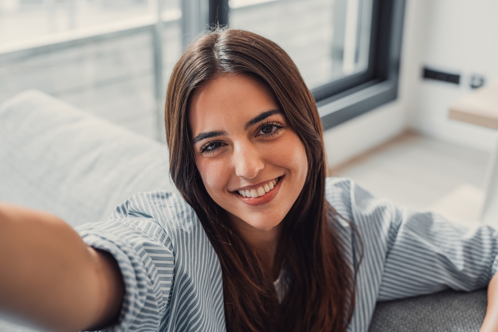 Happy attractive young adult woman housewife sitting on sofa - dental emergency