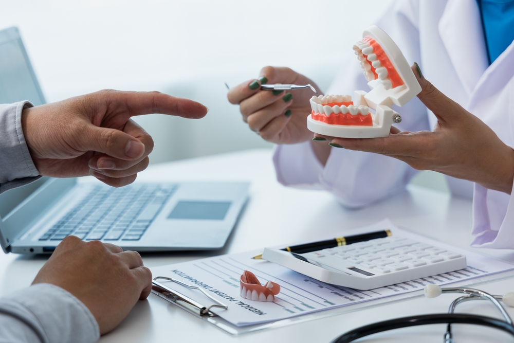 A dentist explaining a dental model to a patient during a consultation  A dentist explaining a dental model to a patient during a consultation