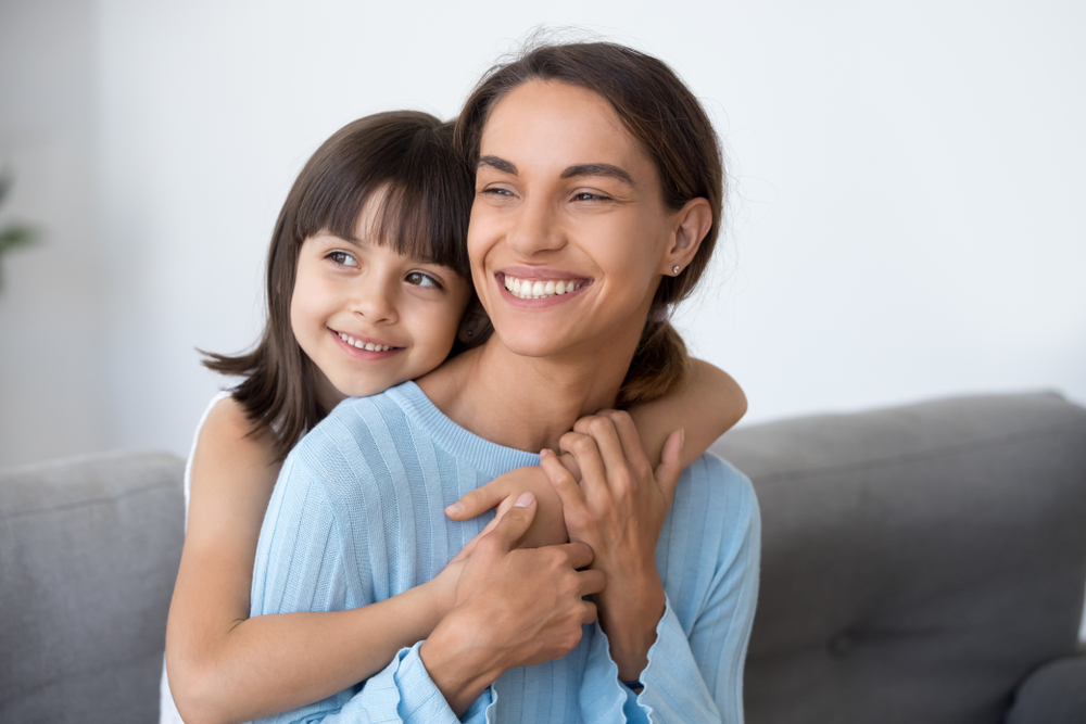 A joyful mother and daughter share a warm embrace while smiling brightly at home, reflecting the confidence and comfort supported by quality family dental care – Dentist in South Hill WA